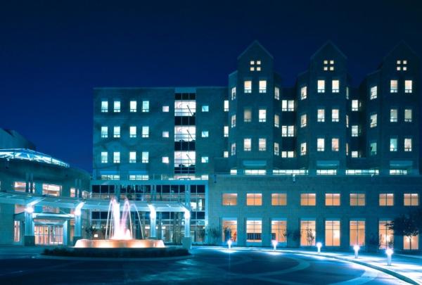 Exterior photo of Wolfson Children's Hospital at night. 蓝色的灯光和喷泉周围的砖圈驱动.